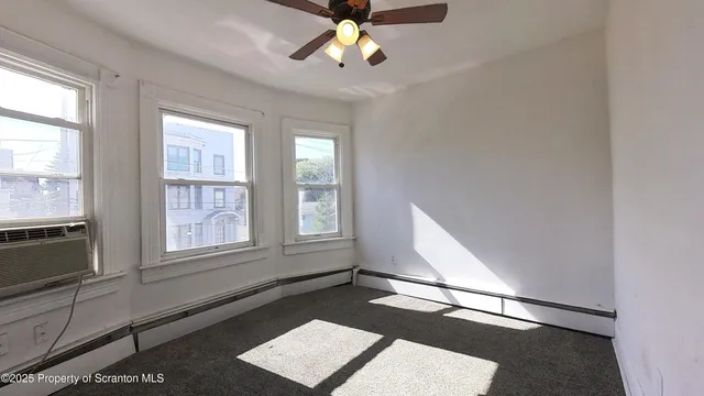 an empty room with windows and ceiling fan