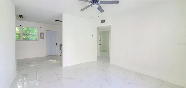 an empty room with a ceiling fan and carpet