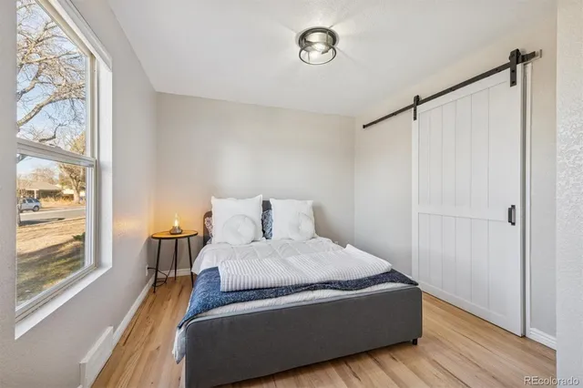 a room with a bed and a window with wooden floor