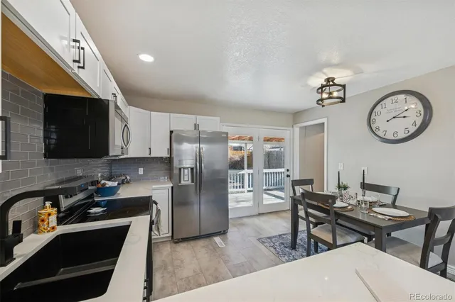 a kitchen with stainless steel appliances granite countertop a refrigerator a stove a sink a dining table and chairs with wooden floor