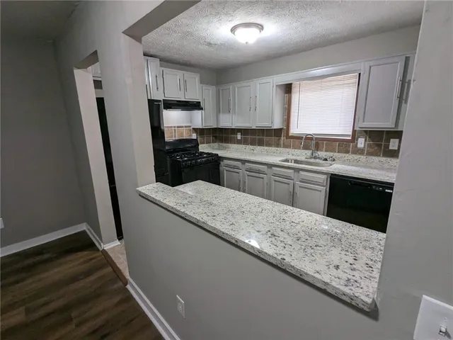 a kitchen with kitchen island granite countertop wooden cabinets a sink a stove a refrigerator and dishwasher