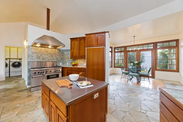 a kitchen with a stove a refrigerator and living room view