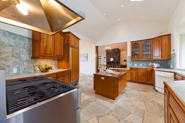 a kitchen with stainless steel appliances granite countertop a stove top oven a sink dishwasher a dining table and chairs with wooden floor