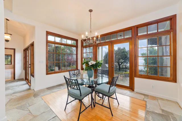 a dining room with furniture large windows and wooden floor
