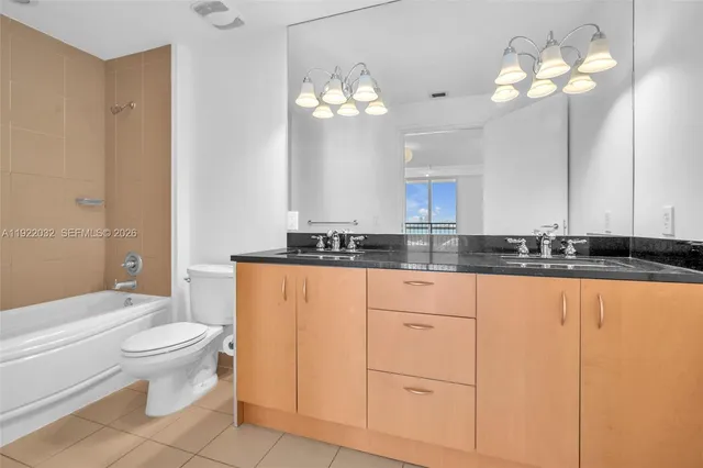 a bathroom with a granite countertop sink a toilet and a large mirror