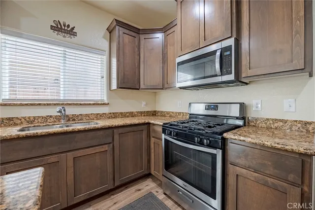 a kitchen with granite countertop stainless steel appliances a stove microwave and sink