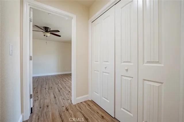 a view of a hallway with wooden floor and closet area