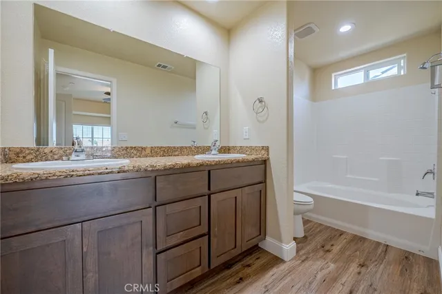 a bathroom with a granite countertop sink a toilet mirror and bathtub