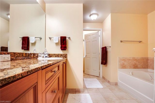 a bathroom with a granite countertop sink and a bathtub