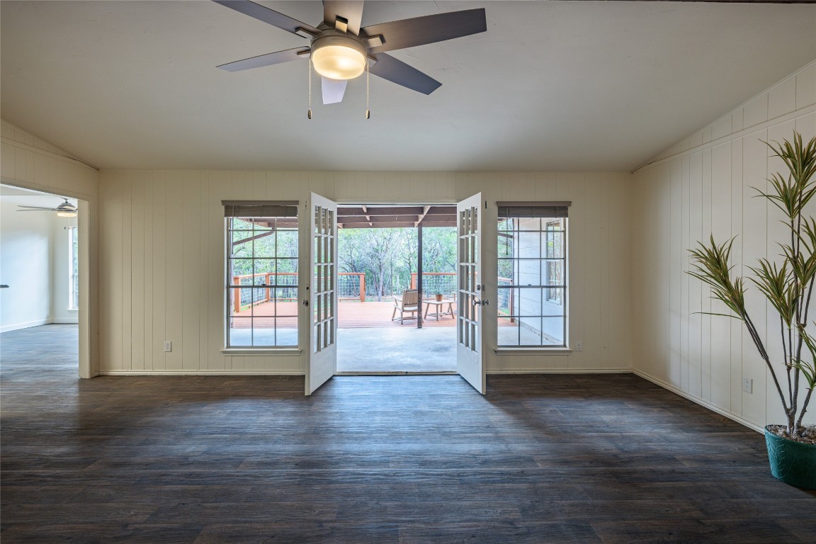 an empty room with wooden floor and windows with curtains
