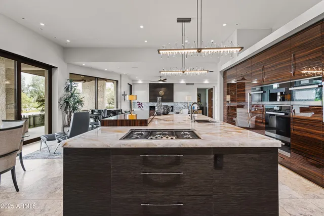 a view of a kitchen with kitchen island a counter top space a sink stainless steel appliances and a large window