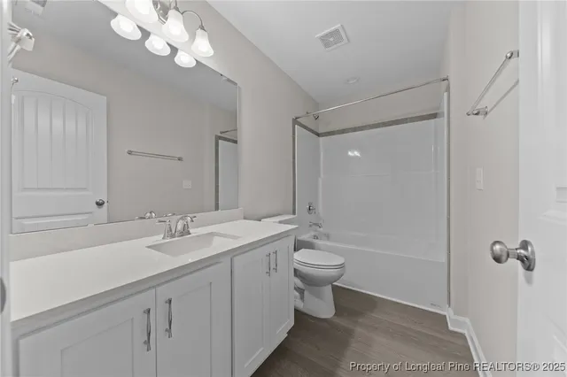 a bathroom with a double vanity sink a toilet and shower