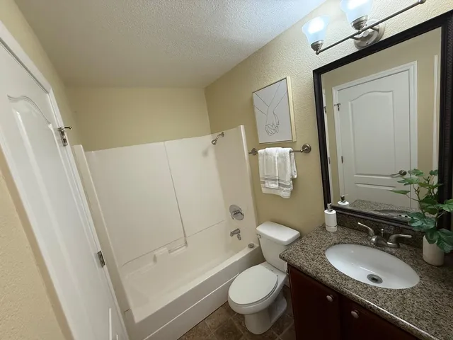 a bathroom with a granite countertop sink toilet mirror and shower