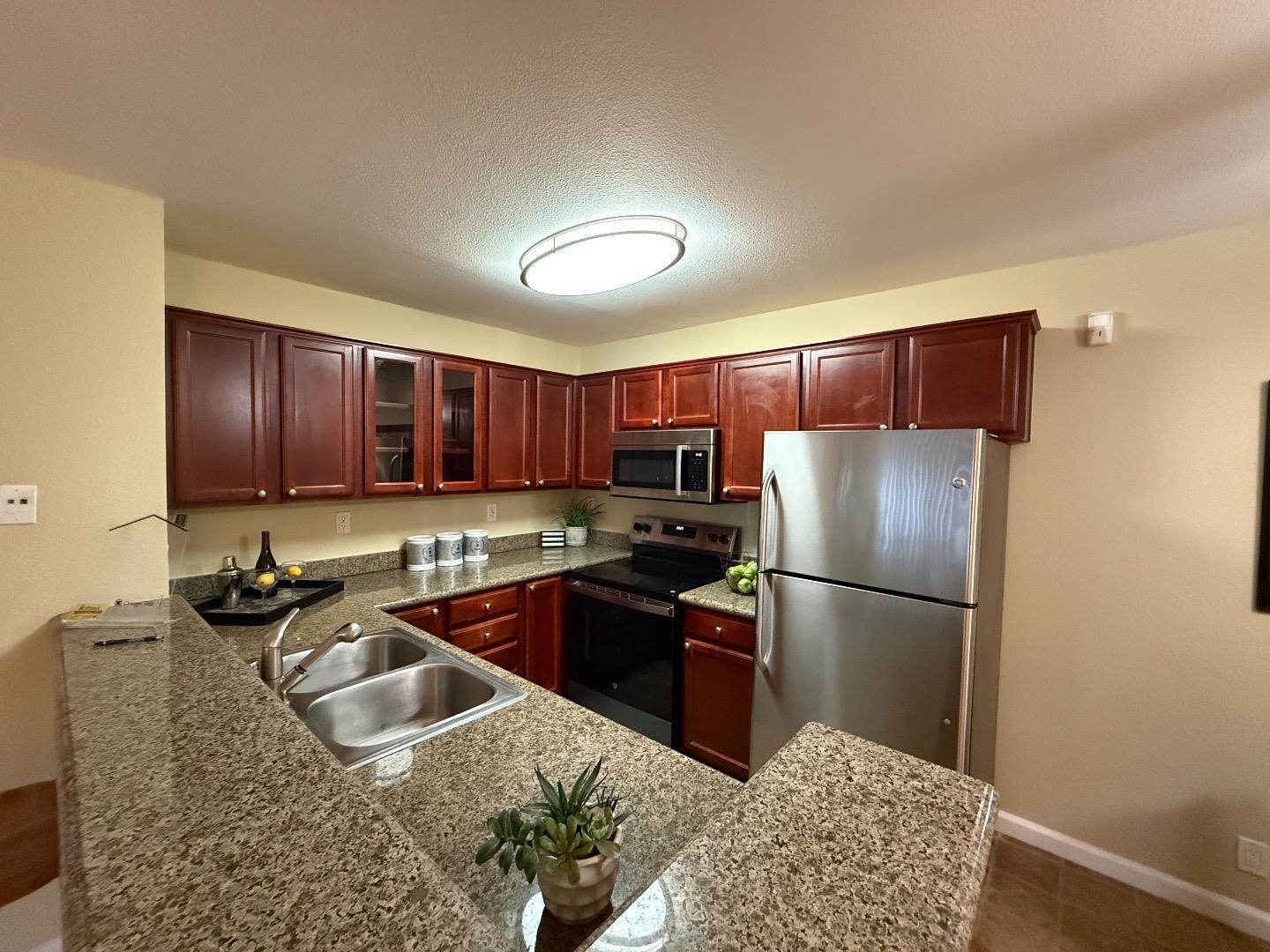 496 Dempsey Road, Unit 199 Milpitas, CA 95035 - Photo 3 of 41 a kitchen with kitchen island granite countertop a sink cabinets and stainless steel appliances
