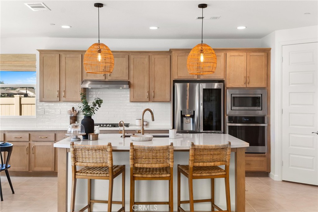 32259 Hillstone Street Temecula, CA 92591 - Photo 7 of 62 a kitchen with stainless steel appliances kitchen island granite countertop a dining table chairs sink and cabinets