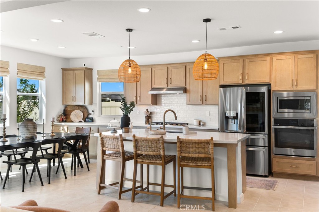 32259 Hillstone Street Temecula, CA 92591 - Photo 8 of 62 a kitchen with stainless steel appliances granite countertop a stove top oven a sink a dining table and chairs