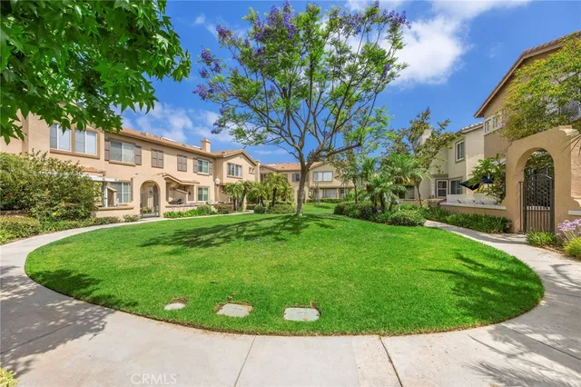 a view of a white house with a big yard plants and large trees