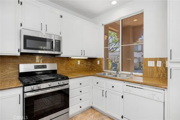 a kitchen with granite countertop a stove a sink and a microwave