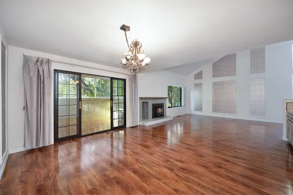 a view of empty room with wooden floor and fireplace