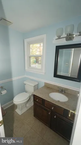 a bathroom with a granite countertop sink toilet and mirror