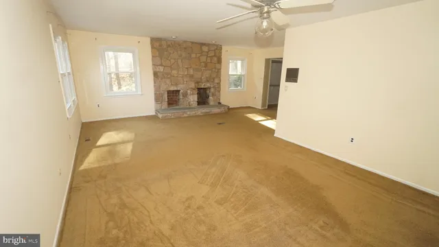 an empty room with a fireplace and windows