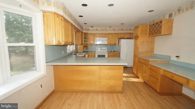 a large kitchen with stainless steel appliances granite countertop a refrigerator a sink dishwasher a stove and a dining table with wooden floor