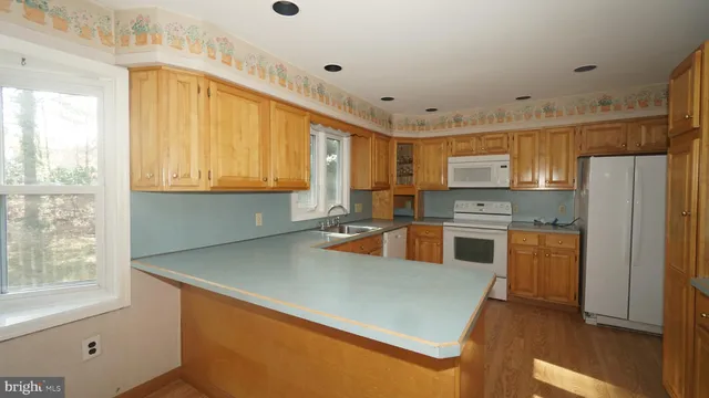 a kitchen with stainless steel appliances granite countertop a refrigerator a sink dishwasher a stove and white countertops with wooden floor