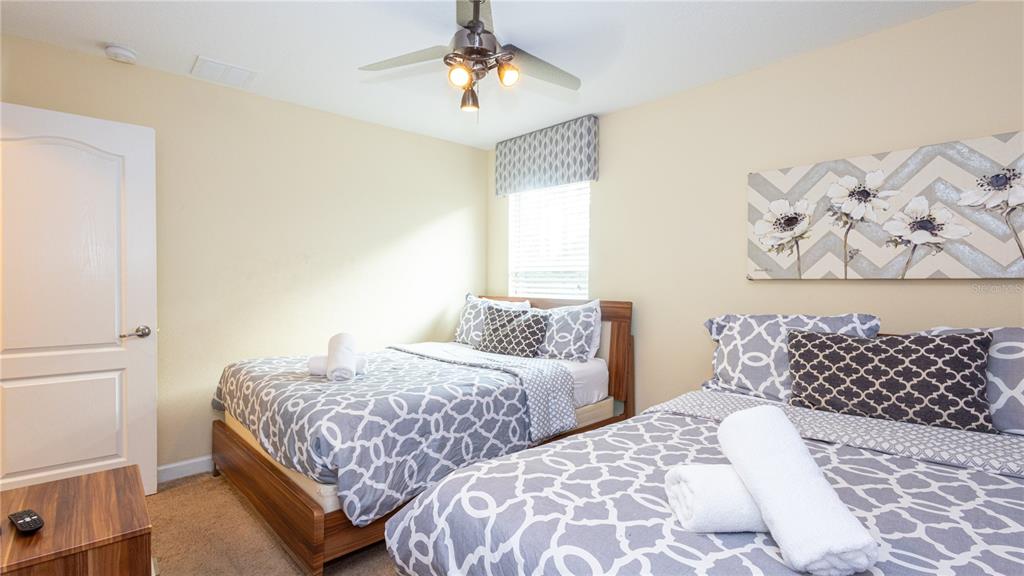 2977 Buccaneer Palm Road Kissimmee, FL 34747 - Photo 25 of 66 a bedroom with two beds and a lamp on dresser