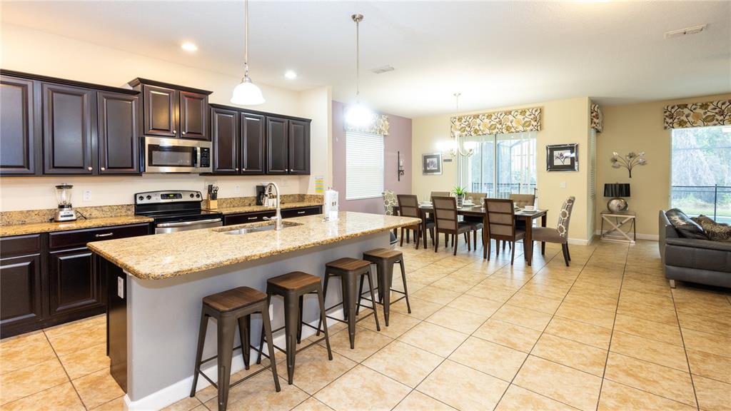 2977 Buccaneer Palm Road Kissimmee, FL 34747 - Photo 10 of 66 a kitchen with stainless steel appliances granite countertop a stove top oven a sink a dining table and chairs
