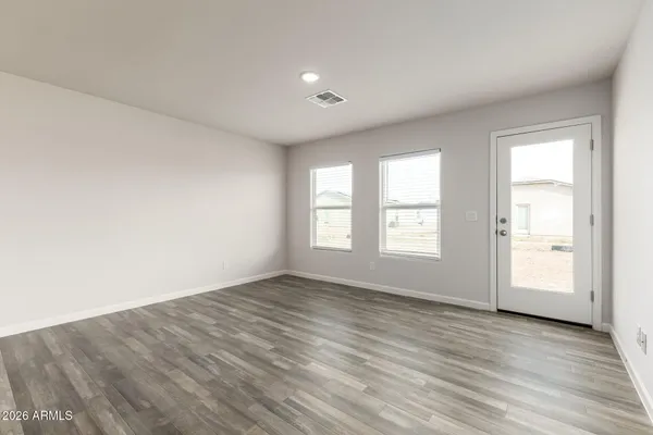an empty room with wooden floor and windows