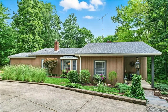 a view of a house with brick walls plants and large tree