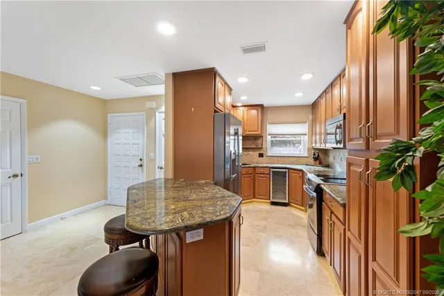 a kitchen with stainless steel appliances kitchen island granite countertop a table chairs in it and wooden floors