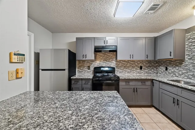a kitchen with stainless steel appliances granite countertop a refrigerator and a stove top oven