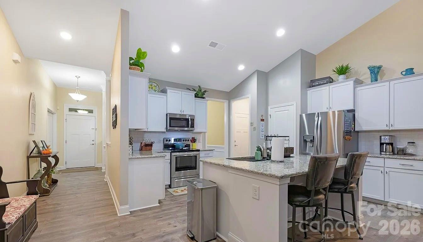 144 Sugar Hill Road Troutman, NC 28166 - Photo 6 of 18 a kitchen with stainless steel appliances kitchen island granite countertop a refrigerator a sink a stove a dining table and chairs