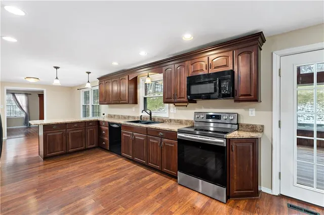 a large kitchen with stainless steel appliances granite countertop wooden cabinets a sink a stove a dining table and chairs