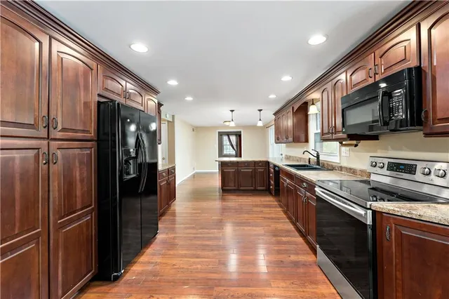 a large kitchen with stainless steel appliances granite countertop a refrigerator and a stove top oven