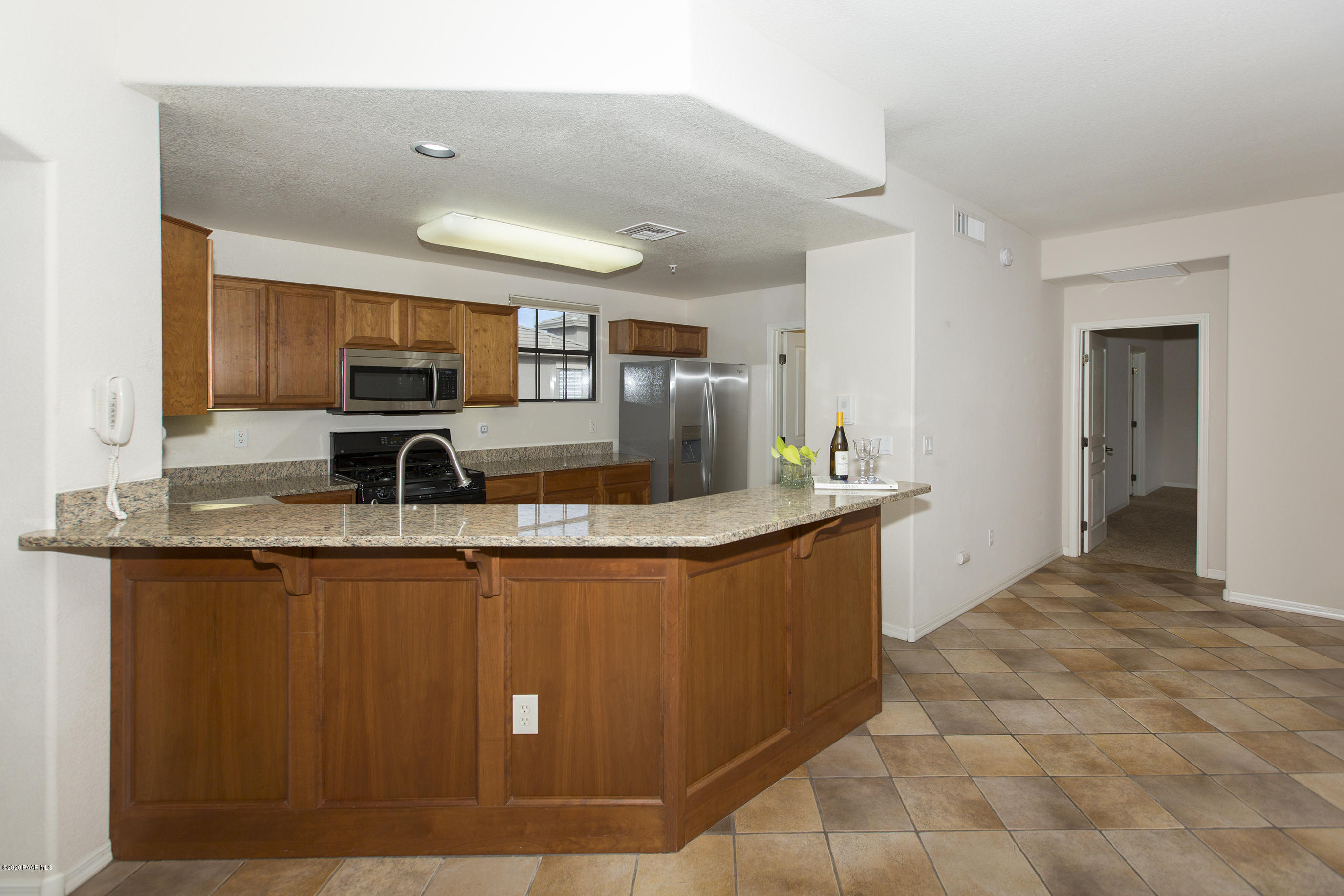 1716 Alpine Meadows Lane, Unit 403 Prescott, AZ 86303 - Photo 9 of 39 a large kitchen with kitchen island granite countertop a sink and cabinets