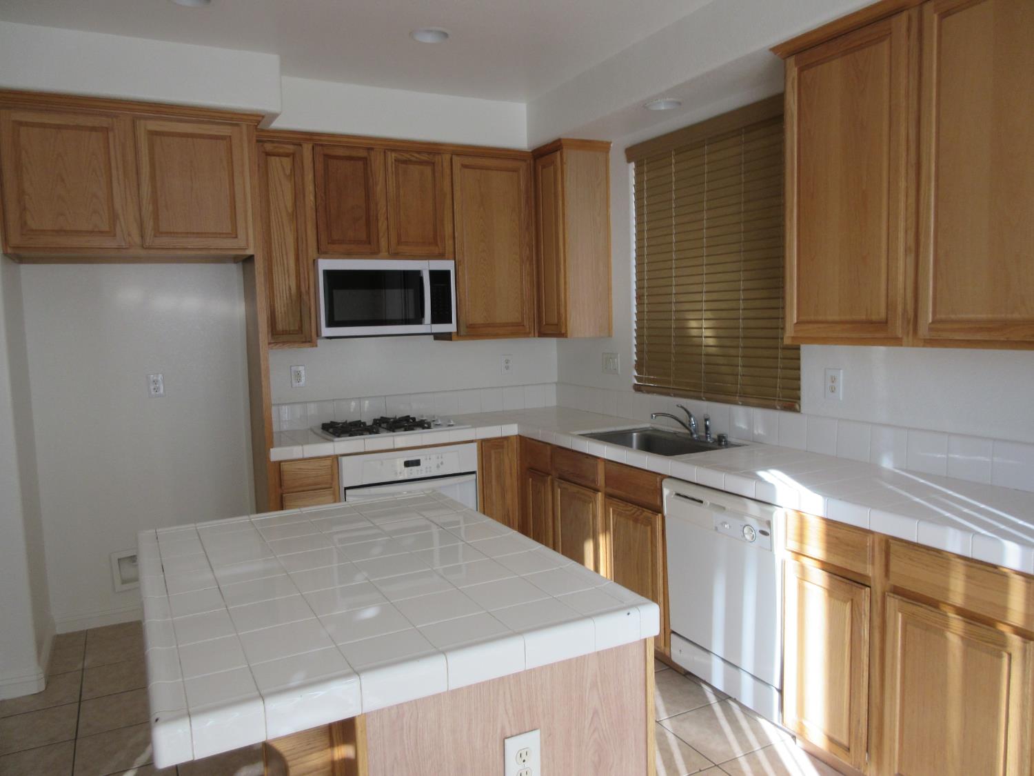 1016 Papaya Street Madera, CA 93638 - Photo 11 of 29 a kitchen with stainless steel appliances a stove sink microwave and cabinets