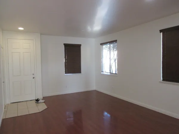 a view of an empty room with wooden floor and a window