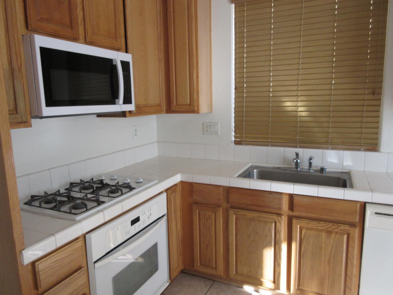 1016 Papaya Street Madera, CA 93638 - Photo 10 of 29 a kitchen with stainless steel appliances a stove microwave and sink