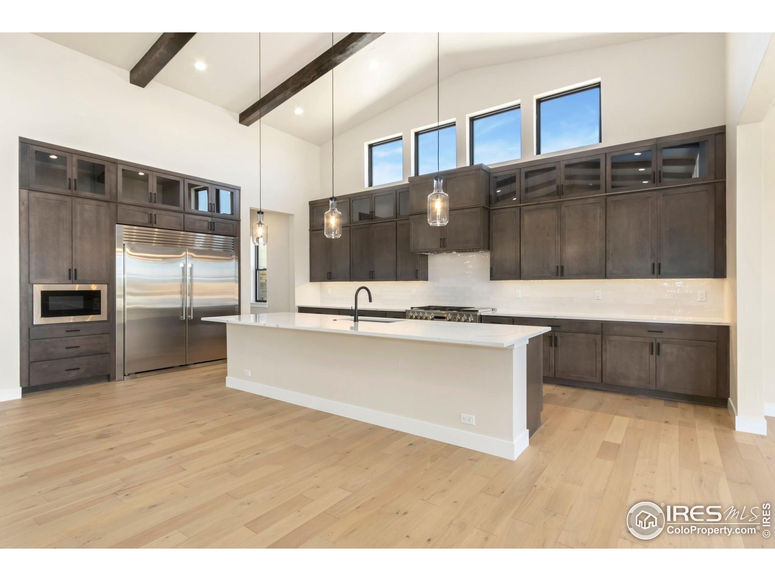 1889 Spring Bloom Drive Windsor, CO 80550 - Photo 6 of 32 a large kitchen with kitchen island a sink stainless steel appliances and cabinets