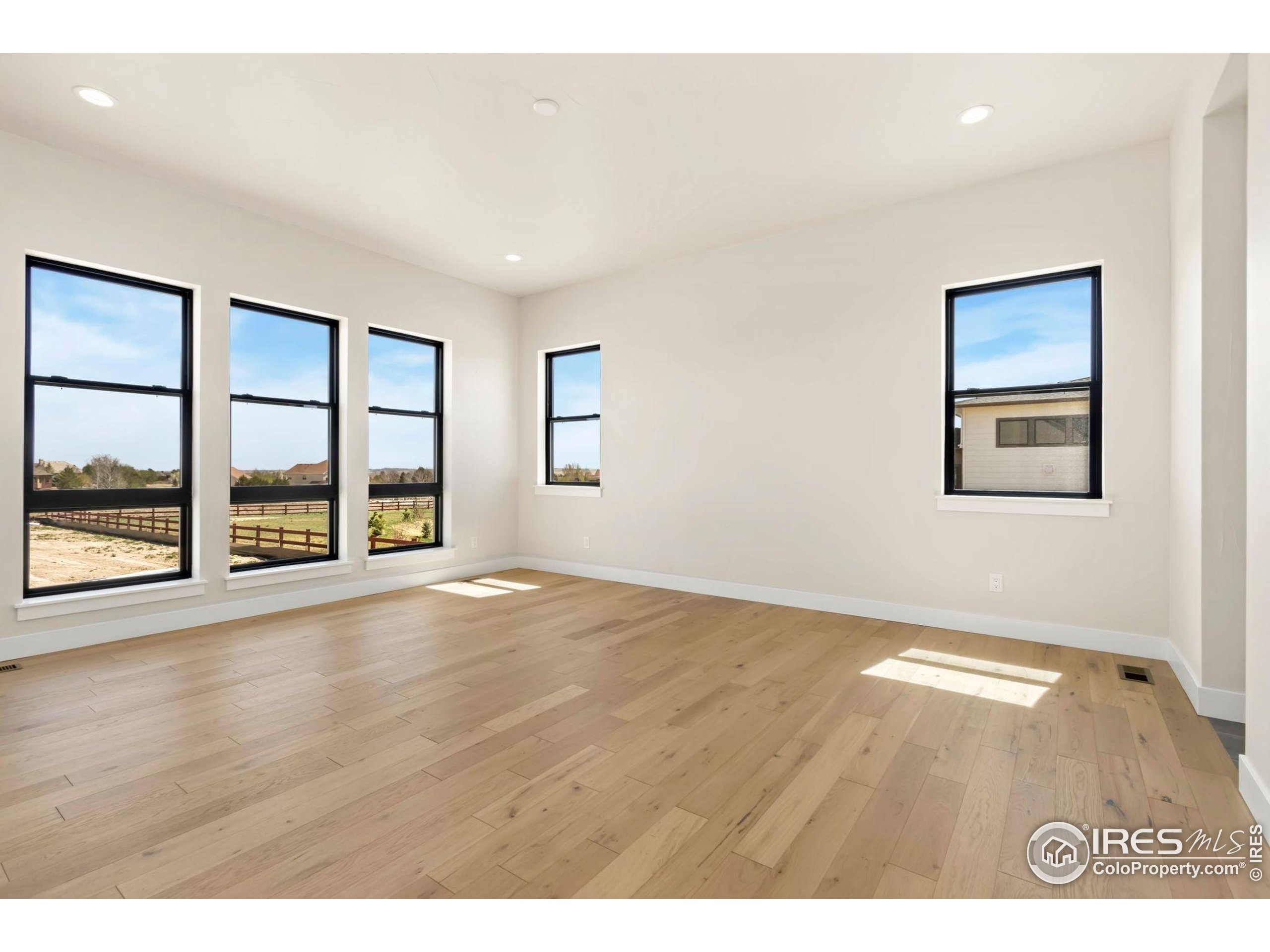 1889 Spring Bloom Drive Windsor, CO 80550 - Photo 8 of 32 a view of an empty room with a window and wooden floor