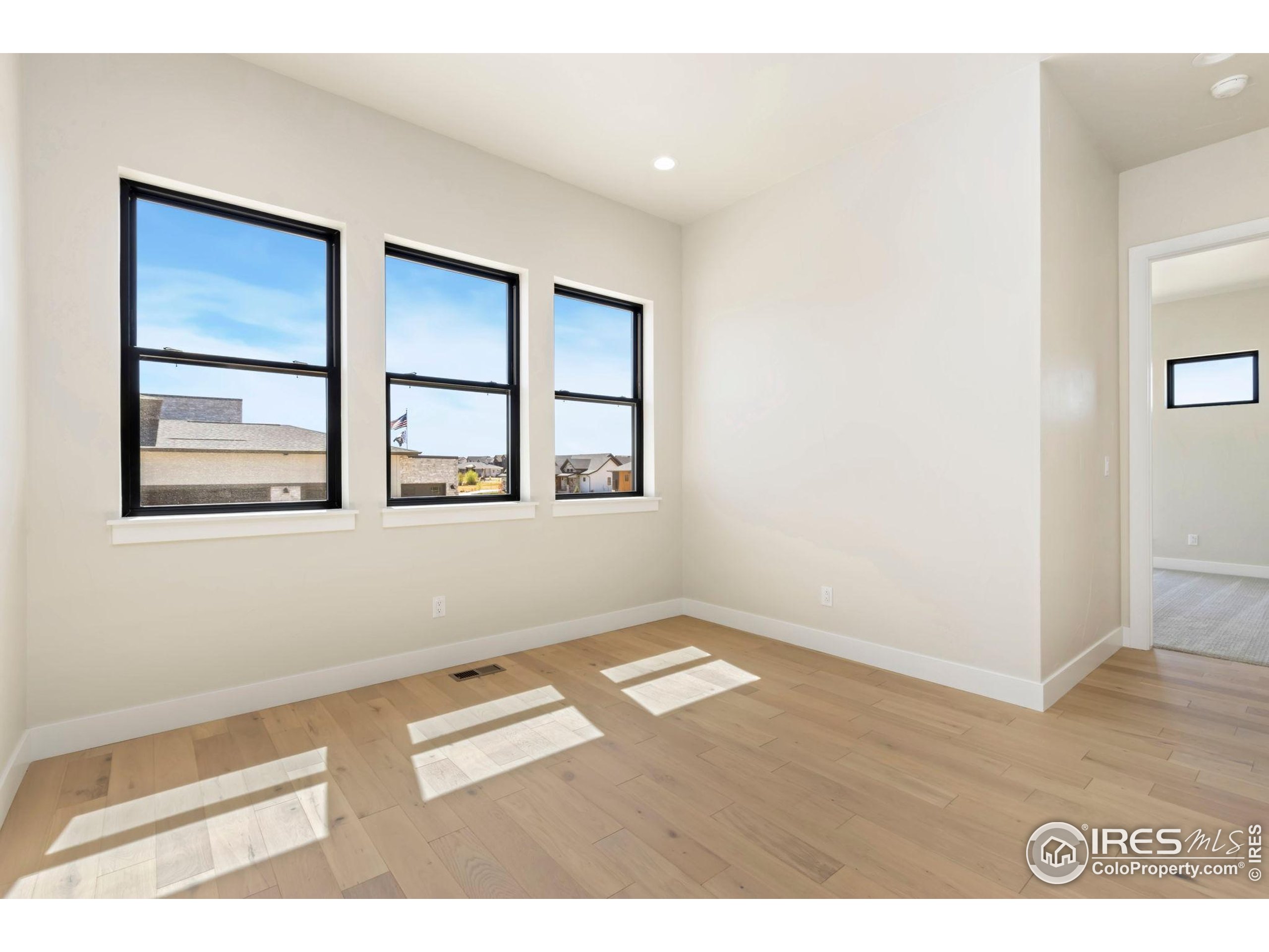 1889 Spring Bloom Drive Windsor, CO 80550 - Photo 10 of 32 a view of an empty room with wooden floor and a window