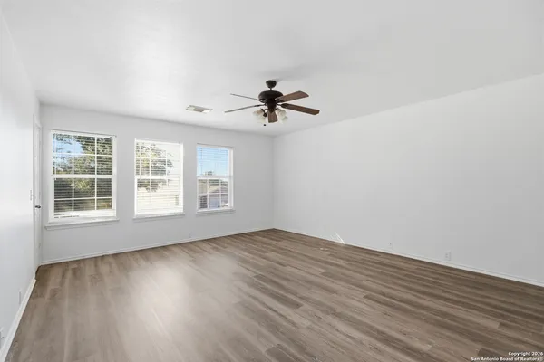 a view of a big room with wooden floor and a ceiling fan