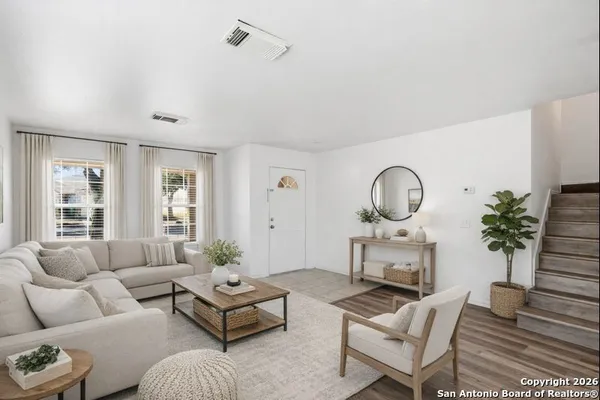 a living room with furniture a rug potted plant and a window