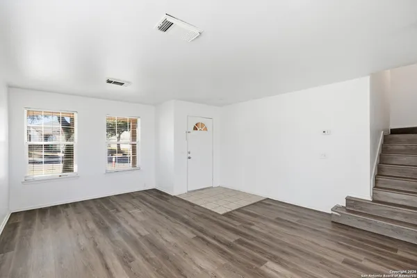 a view of empty room with wooden floor and fan