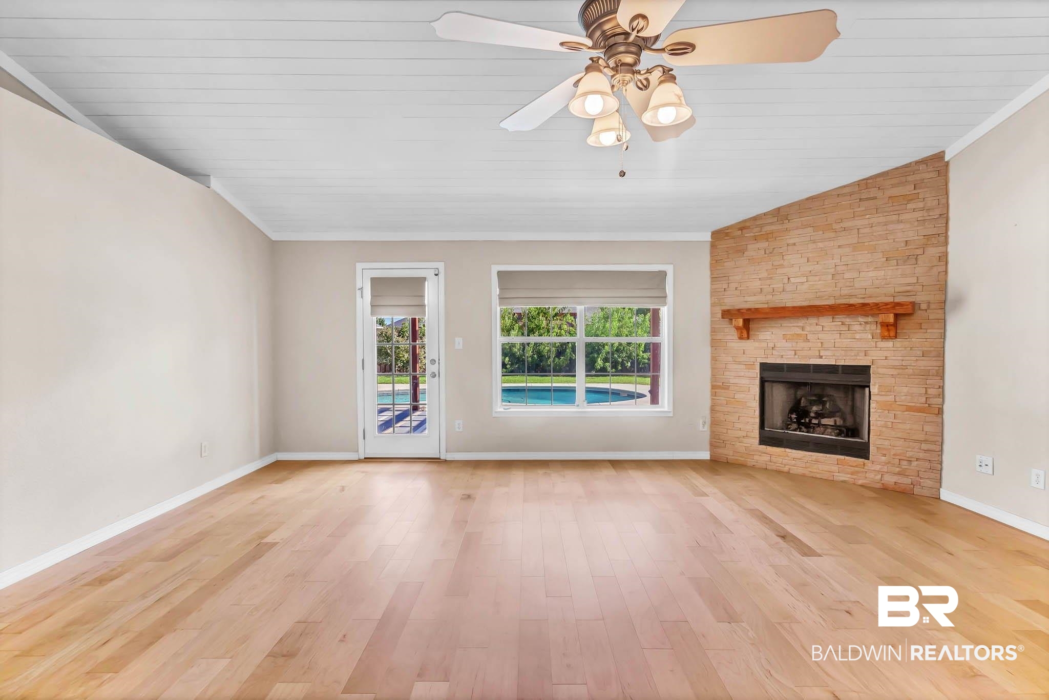 9607 Czar Court Fairhope, AL 36532 - Photo 8 of 42 Unfurnished living room with lofted ceiling, light wood-type flooring, a stone fireplace, a ceiling fan, and crown molding