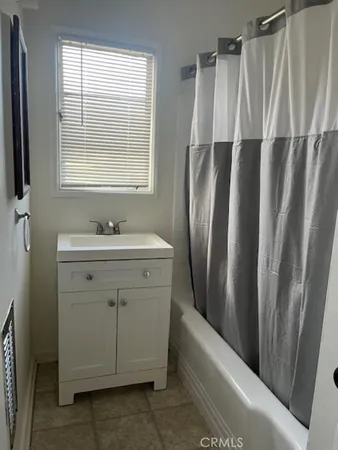 a bathroom with a sink a mirror a bathtub and next to a window