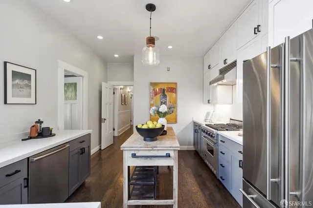 a kitchen with stainless steel appliances kitchen island granite countertop a refrigerator a stove a sink dishwasher and a dining table with wooden floor
