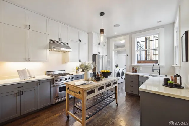a kitchen with a stove a sink and wooden floor